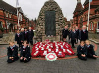 Children lay their hand-made wreath on war memorial